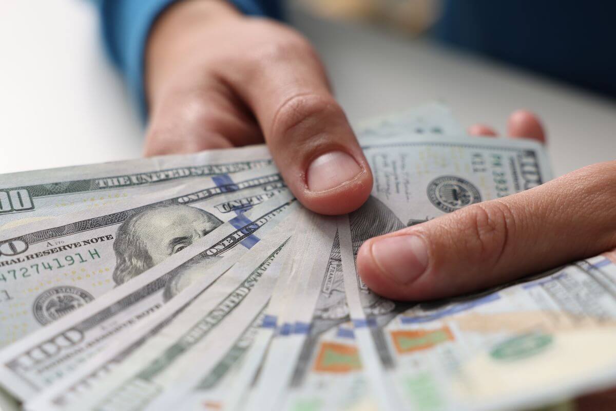 Une image montre une main d'homme tenant de l'argent.