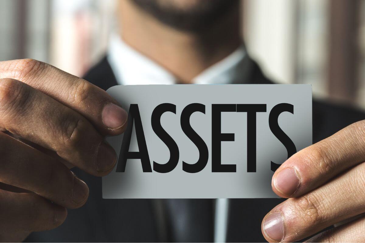 A picture of a man holding a paper with assets written on it.