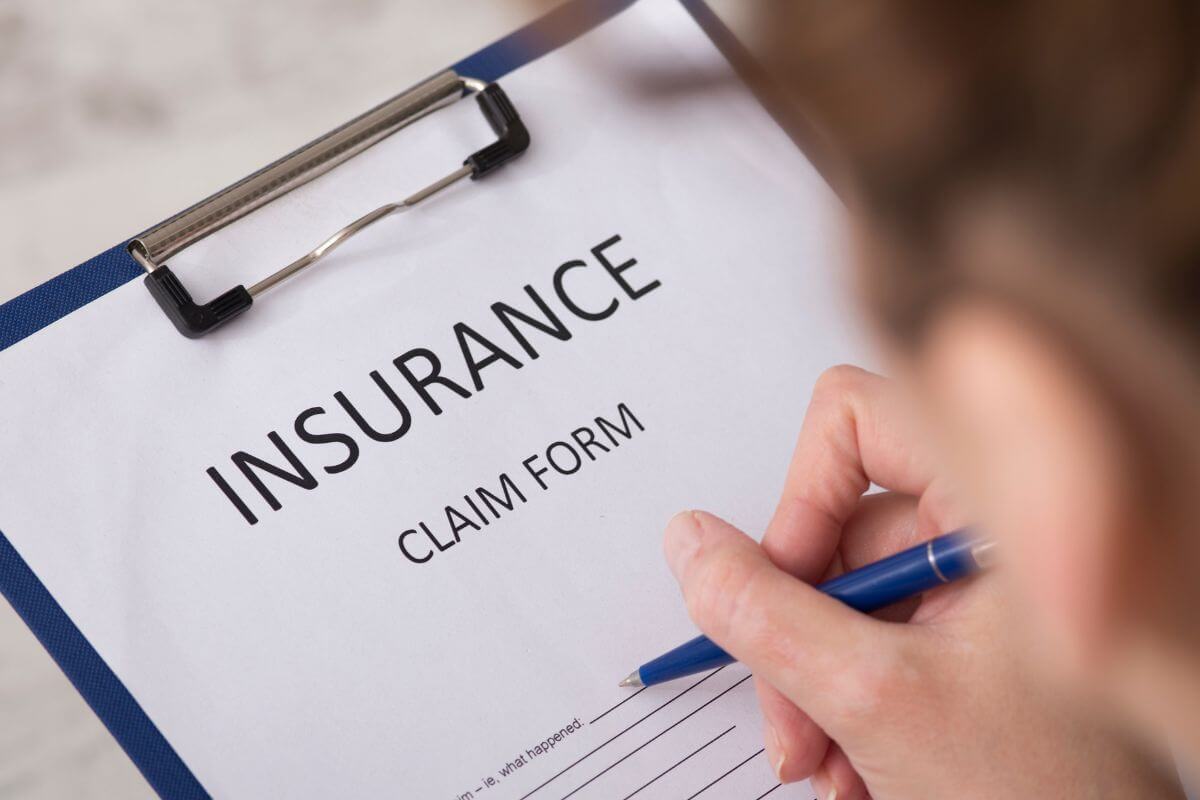 A picture of a man filling out an insurance claim form.