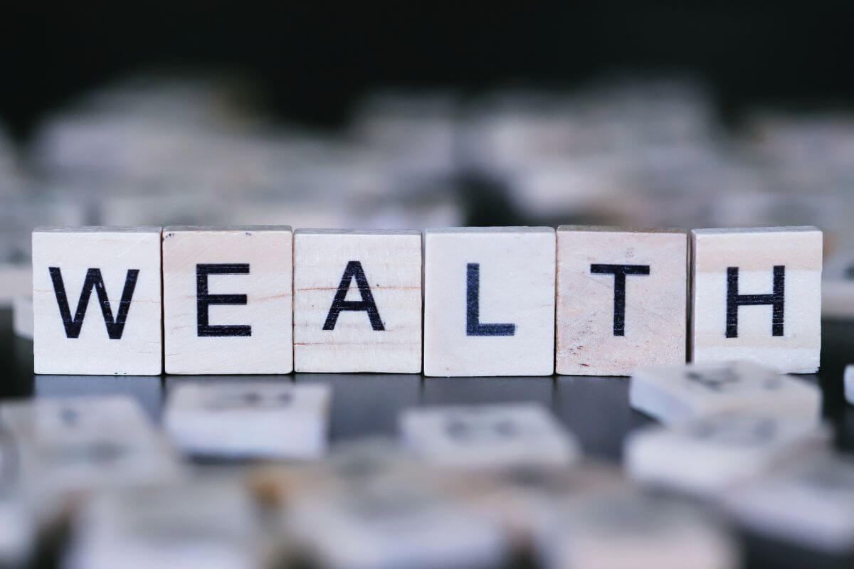 An image shows a wealth wording in wooden cubes.