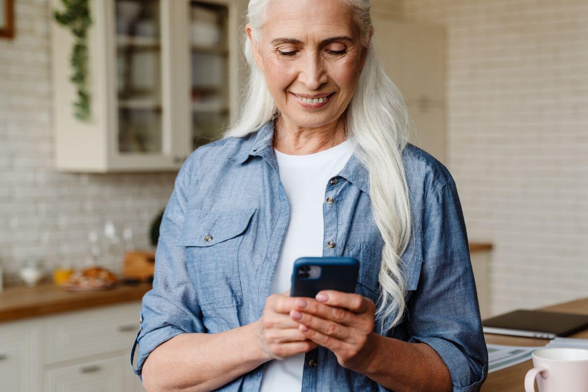 A foto de uma mulher idosa usando um telefone.