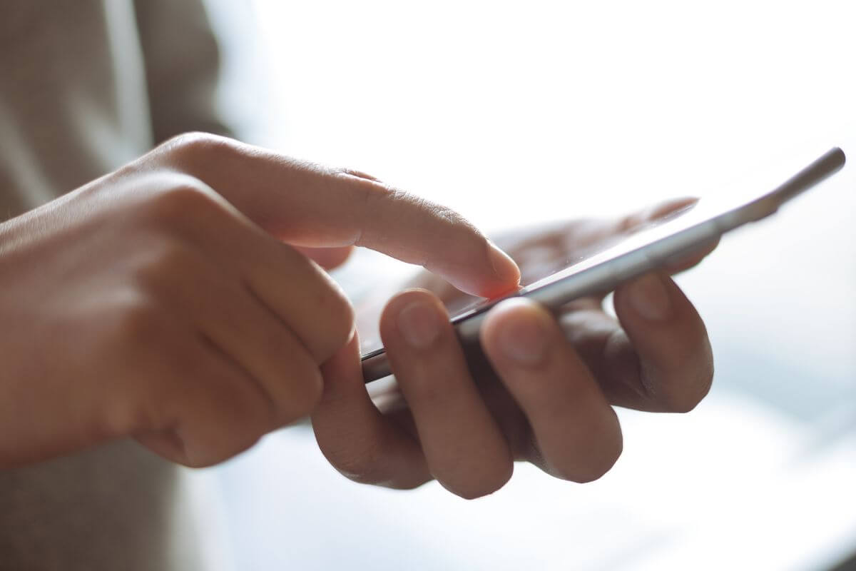 An image of a man's hand using a phone.