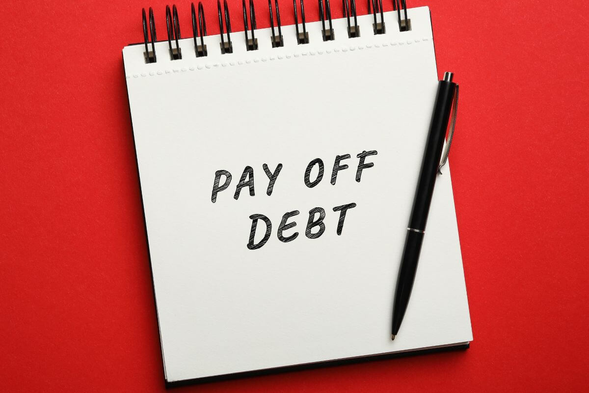 Une image montre un carnet avec 'remboursez vos dettes' écrit dessus.