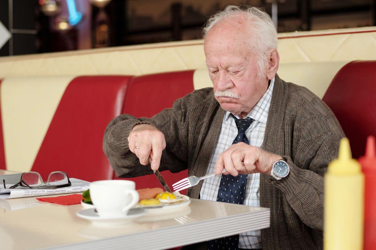 Une image d'un homme âgé mangeant au restaurant.