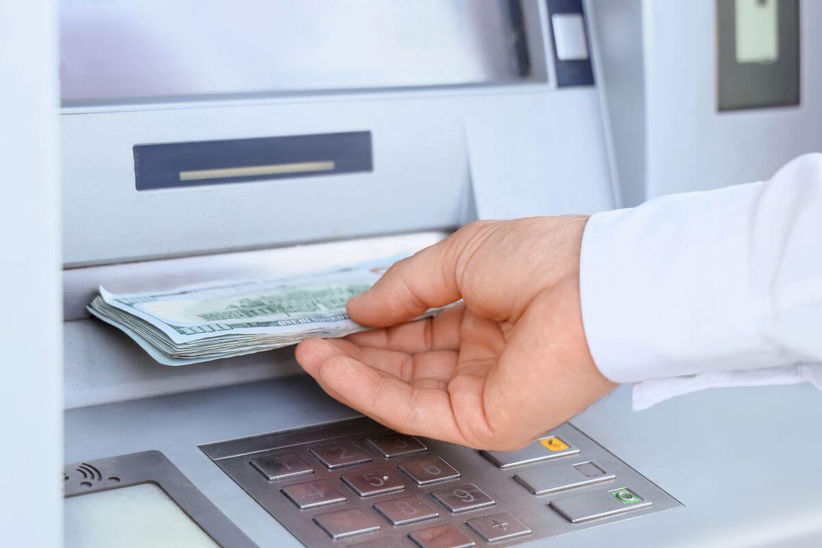 An image shows a man's hand withdrawing money.
