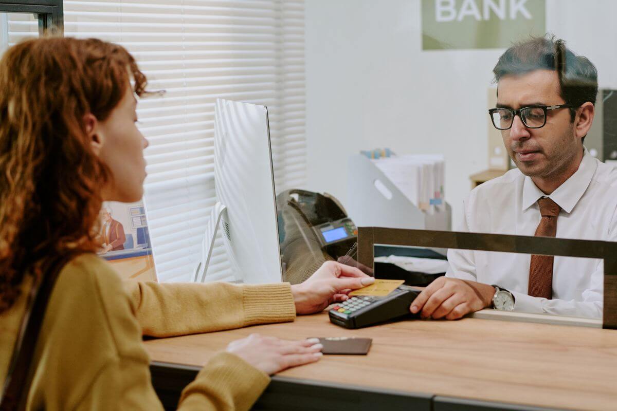 An image shows a customer and a bank teller.