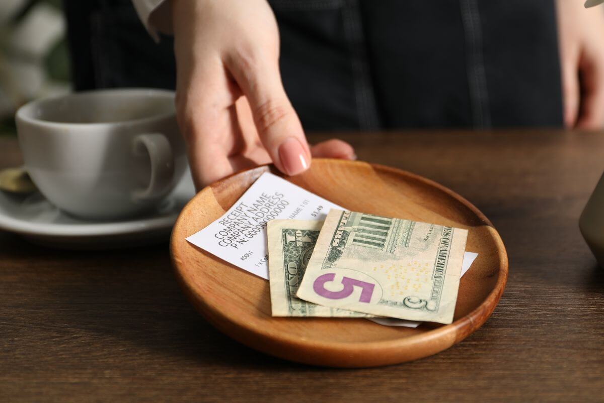 An image shows a waitress receiving her tip.