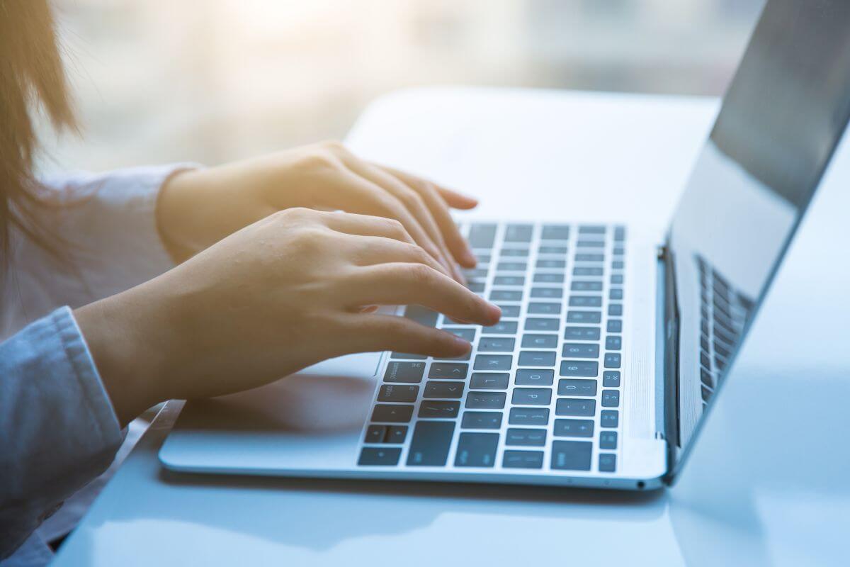 An image shows a woman's hand using a laptop.