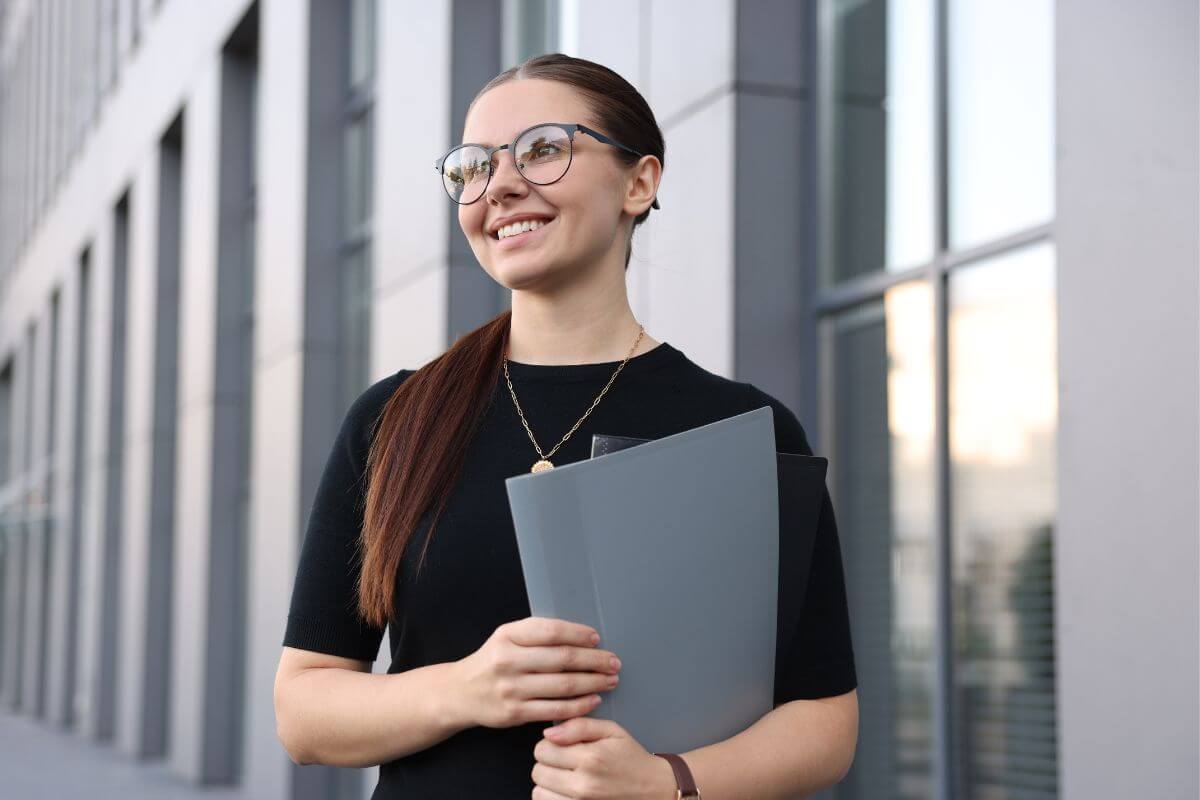 An image shows a woman carrying folders.
