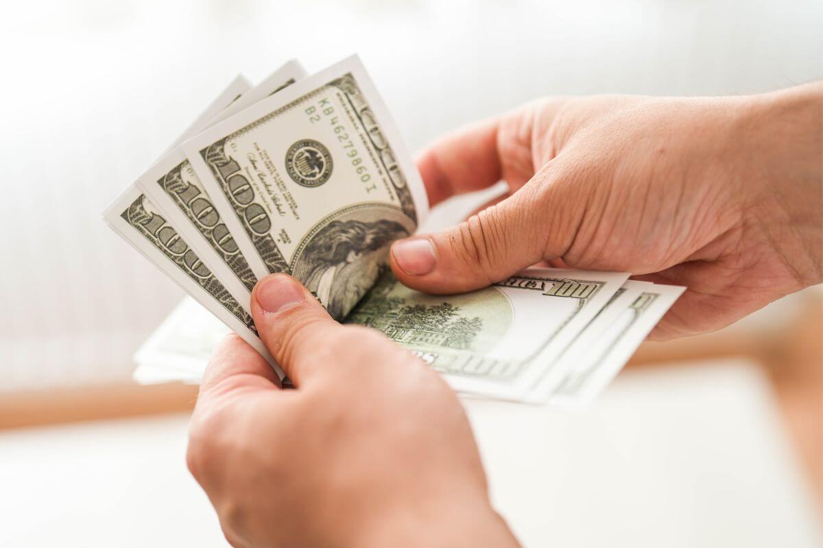 Uma imagem mostra a mão de um homem contando dinheiro.