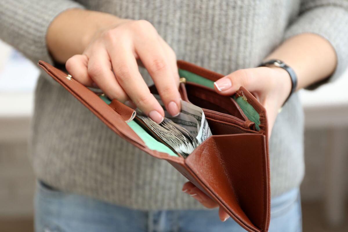 A photo shows a woman taking money from a wallet.