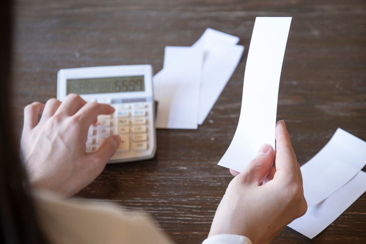 Uma foto mostra uma mulher calculando as receitas.
