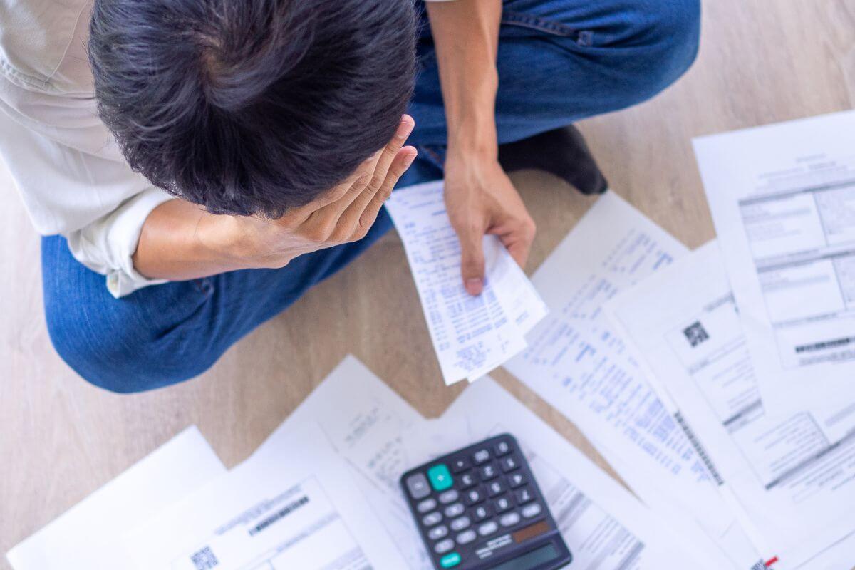 A imagem de um homem preocupado com suas despesas.