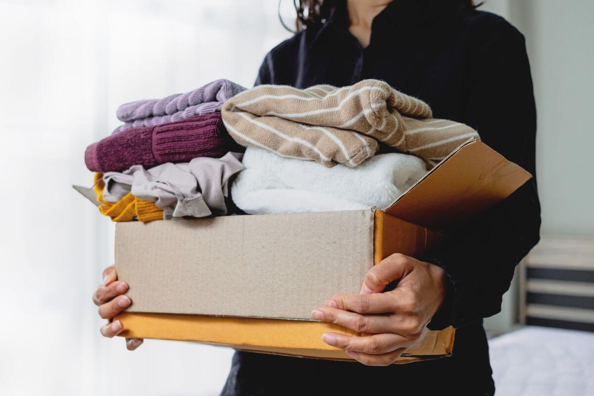 A picture of a woman carrying a box of clothes.