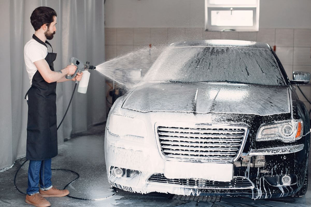 A picture of a man cleaning the car.