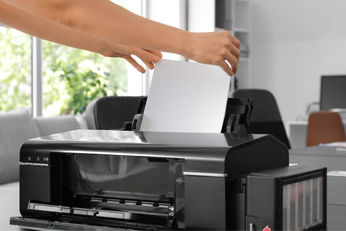 An image of a woman's hand setting up a printer.