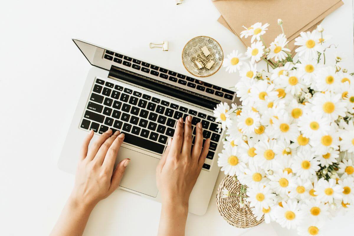 An image of a woman's hand typing on a laptop.