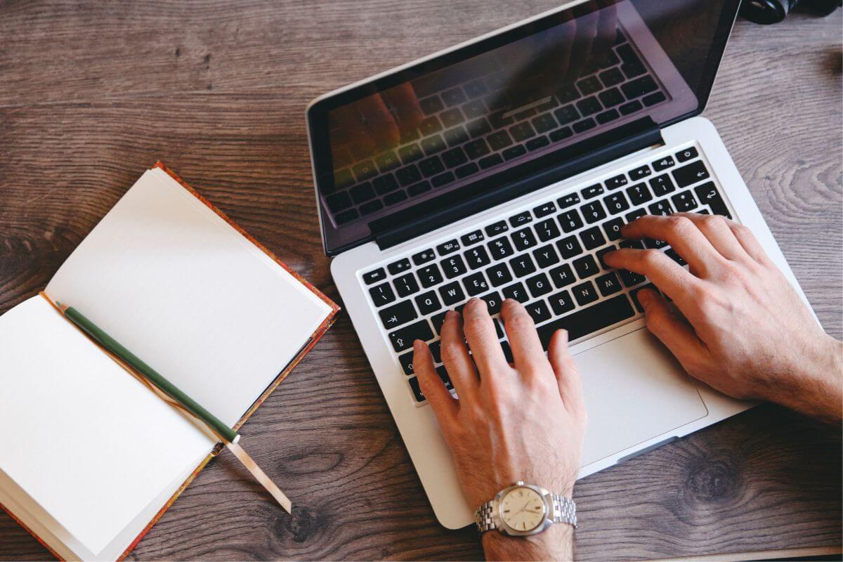 A picture of a man's hand typing on the laptop.