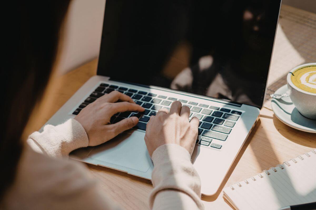 A picture of a woman typing on a laptop.