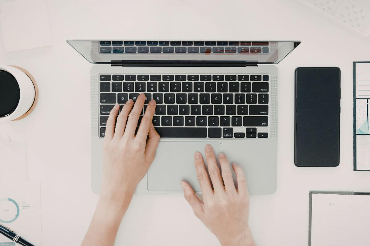 An image shows a woman's hand using a laptop.