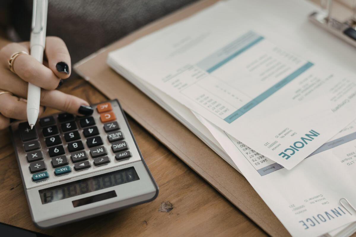 An image of a woman's hand calculating her bills.