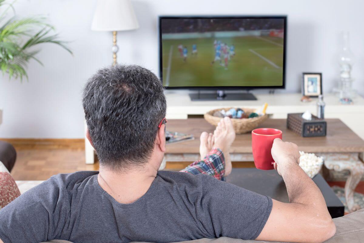 A picture shows a man watching a TV.