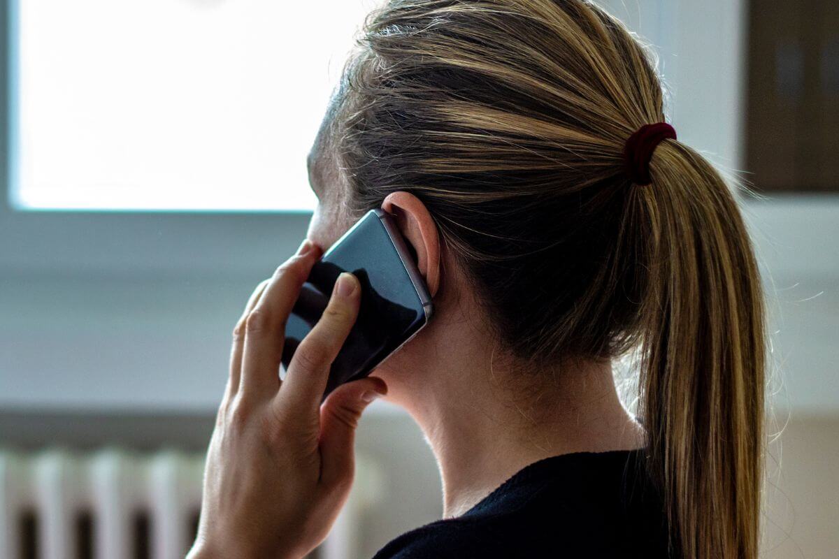 Uma foto mostra uma mulher conversando com alguém ao telefone.