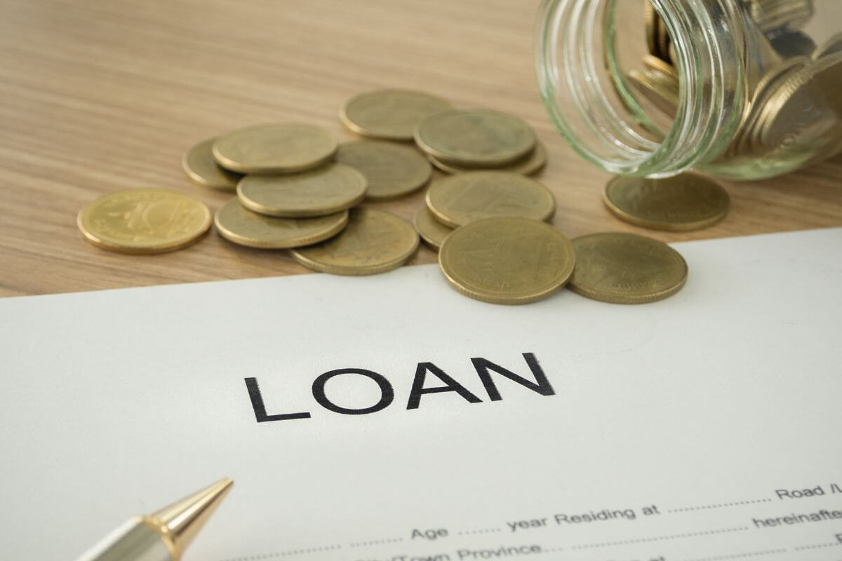 A picture shows a paper with loan wording and coins.