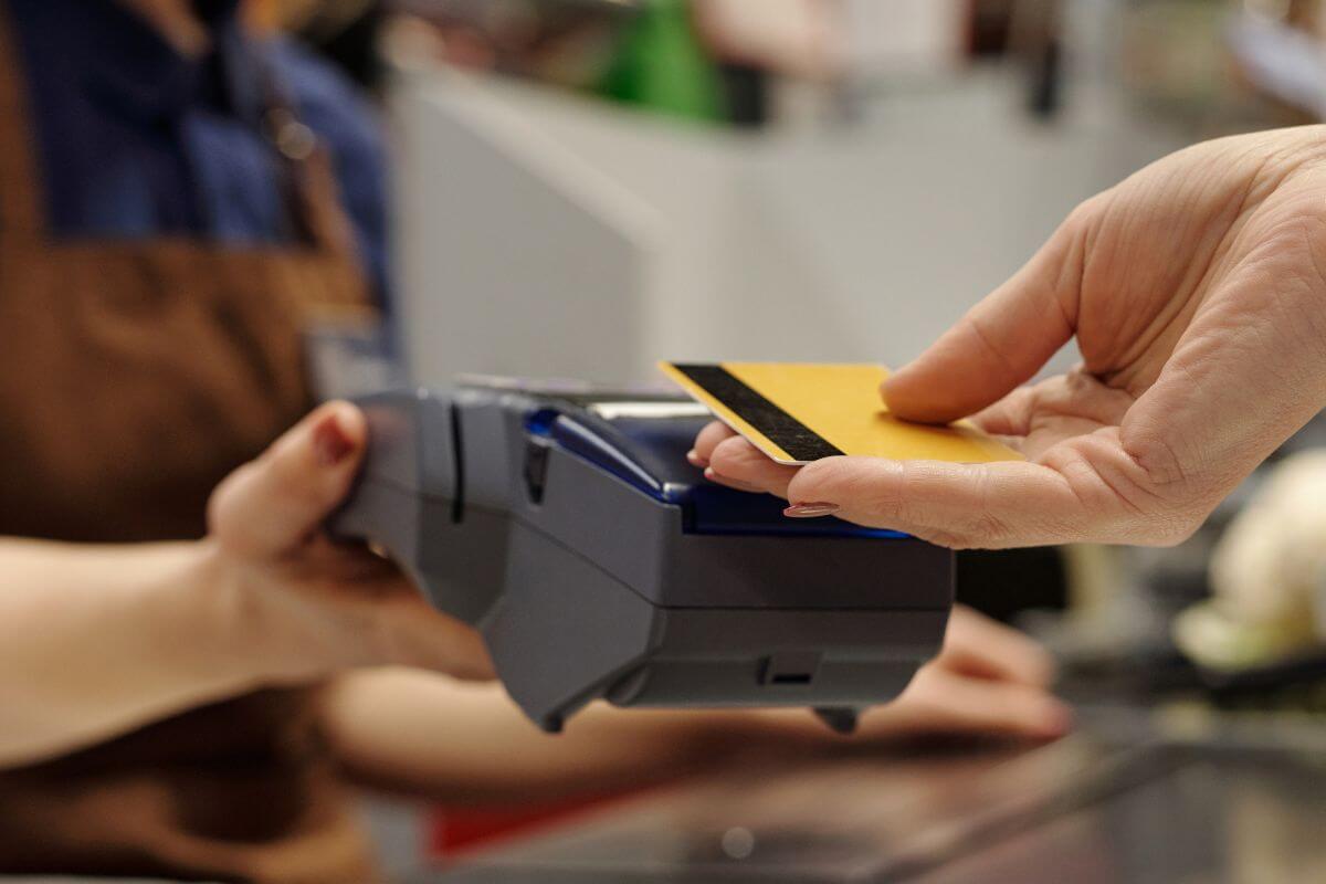 Uma imagem mostra um cliente pagando com cartão de crédito.