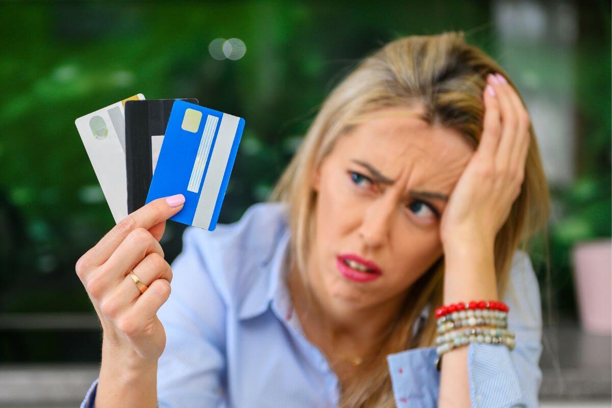 A foto de uma mulher estressada com cartões de crédito.
