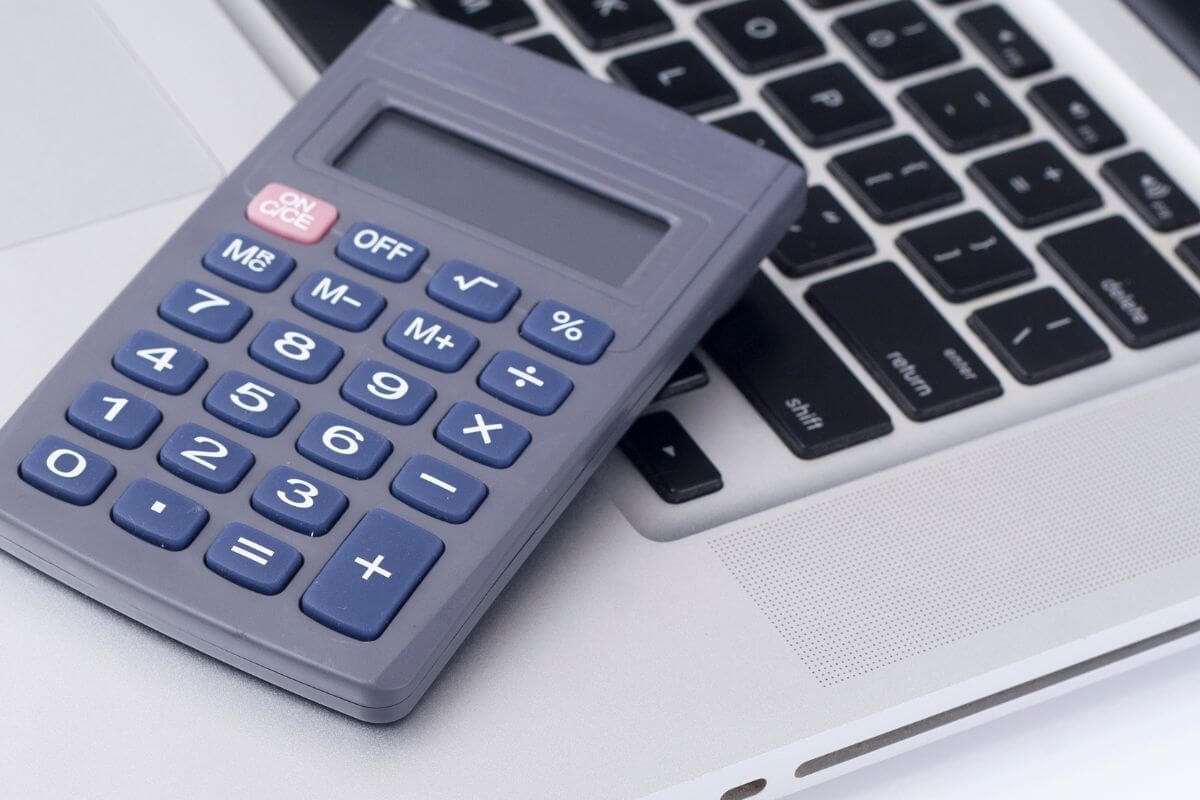 Uma foto de um laptop e uma calculadora.