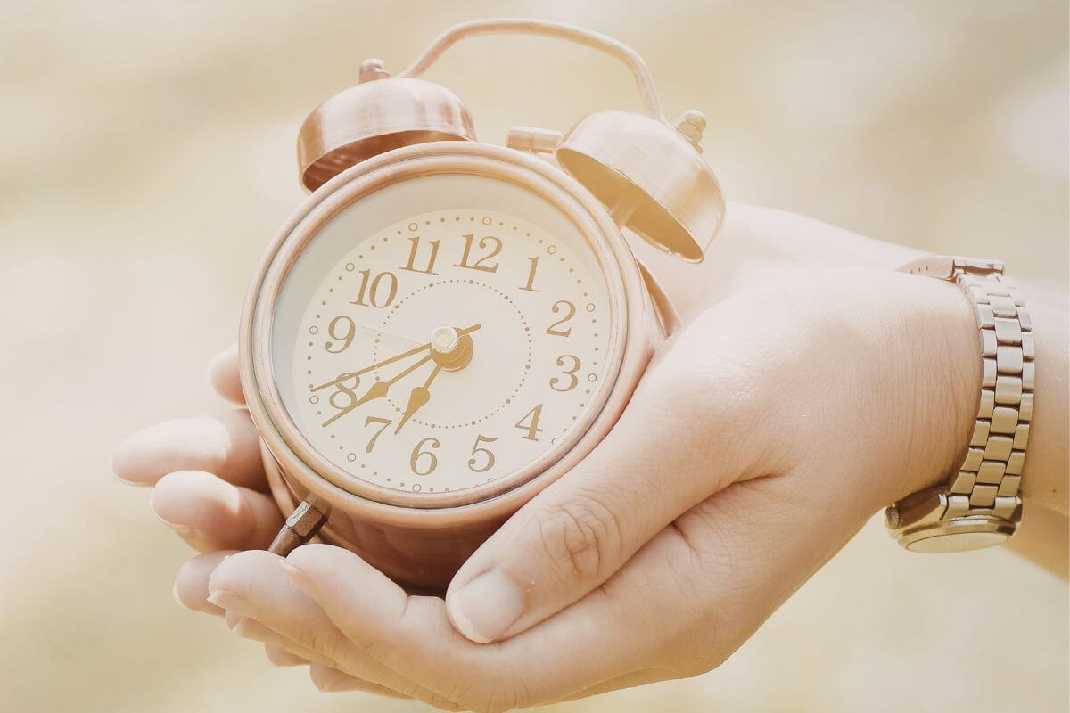 A foto da mão de uma mulher segurando um relógio.