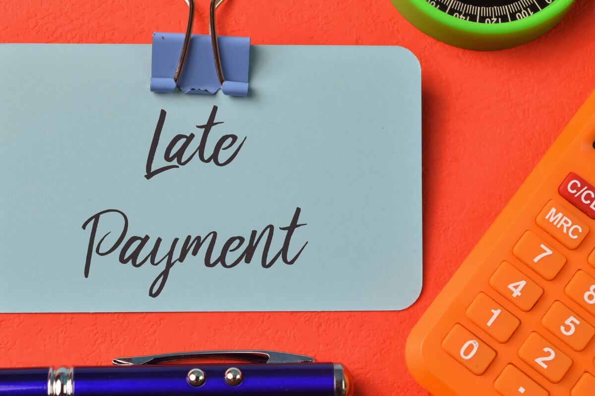 Uma imagem mostra um documento com a redação de atraso de pagamento.