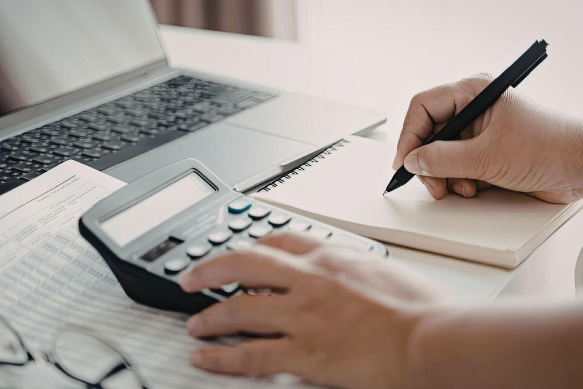 Uma imagem mostra uma pessoa escrevendo em um caderno.