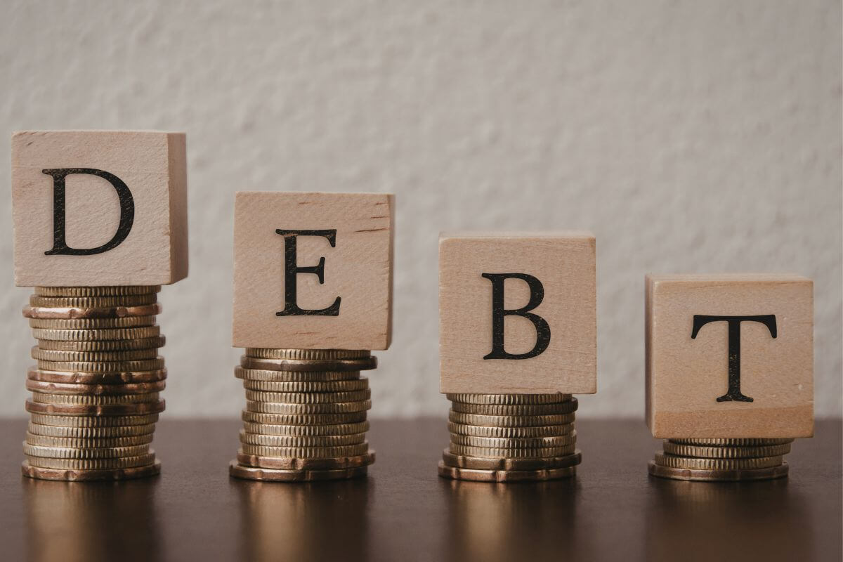 A picture of stacks of coins and debt wording.