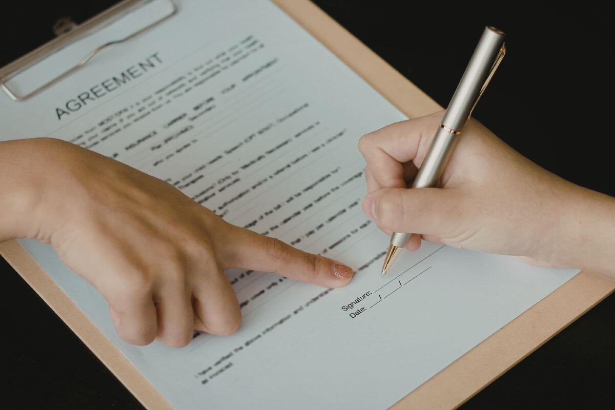 A picture shows two people signing an agreement form.