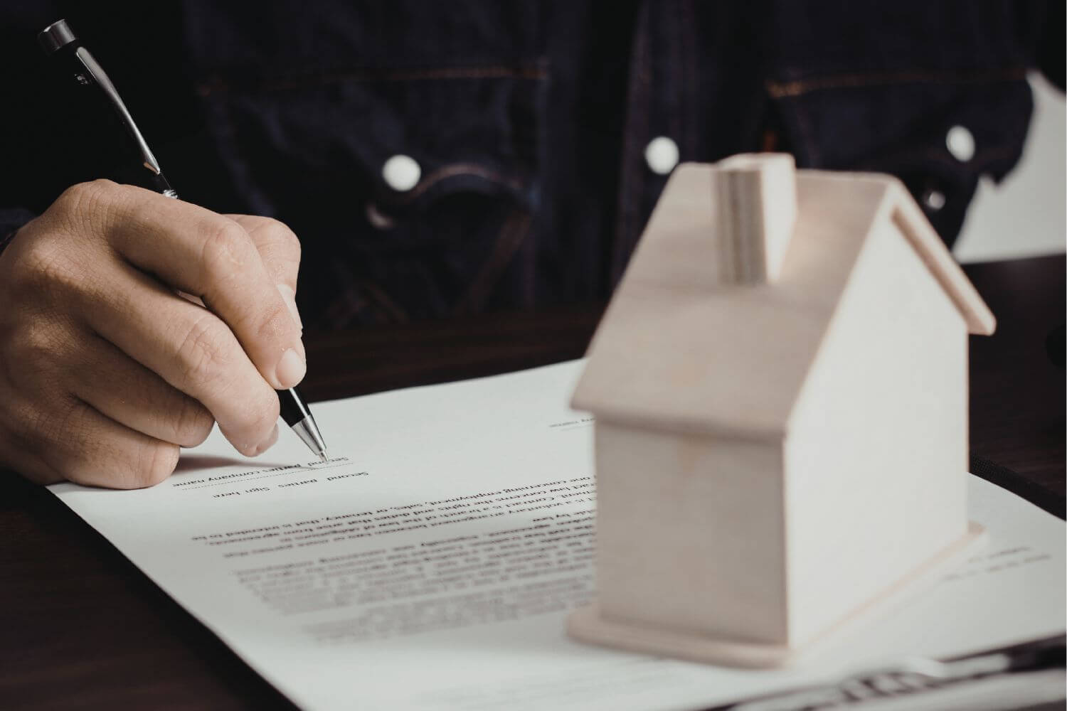 A picture of a house figure and a man signing a document.